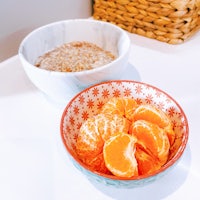 a bowl of sliced oranges next to a bowl of granola