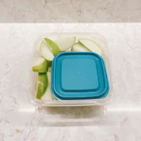 a plastic container with apples in it