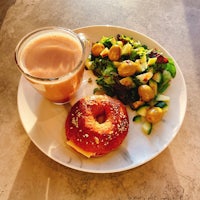 a plate with a bagel, salad and a cup of coffee