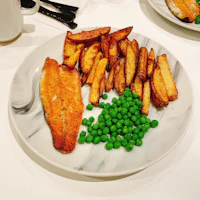 a plate of fish and peas on a table