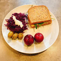 a white plate with a sandwich and red cabbage on it