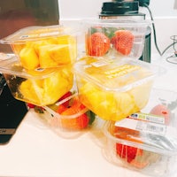 a bunch of fruit in plastic containers on a counter