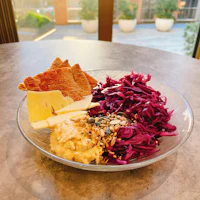 a bowl of red cabbage with cheese and crackers on a table