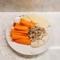 a white plate with carrots, cheese, and hummus
