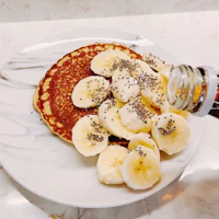 a plate of pancakes with bananas and chia seeds