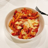 a white bowl of pasta with sauce and a fork
