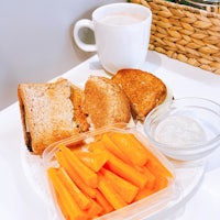 a plate with a sandwich, carrots and a cup of coffee