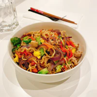 a white bowl with noodles and vegetables in it