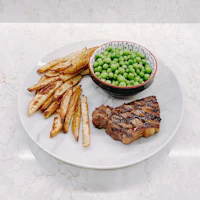 a plate with a steak, peas and fries