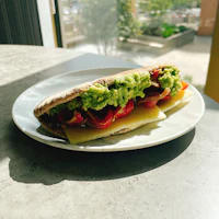 a sandwich on a white plate next to a window