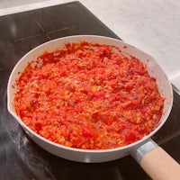 a pan full of red sauce on a stove top