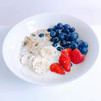 a bowl of oatmeal with berries, bananas and granola